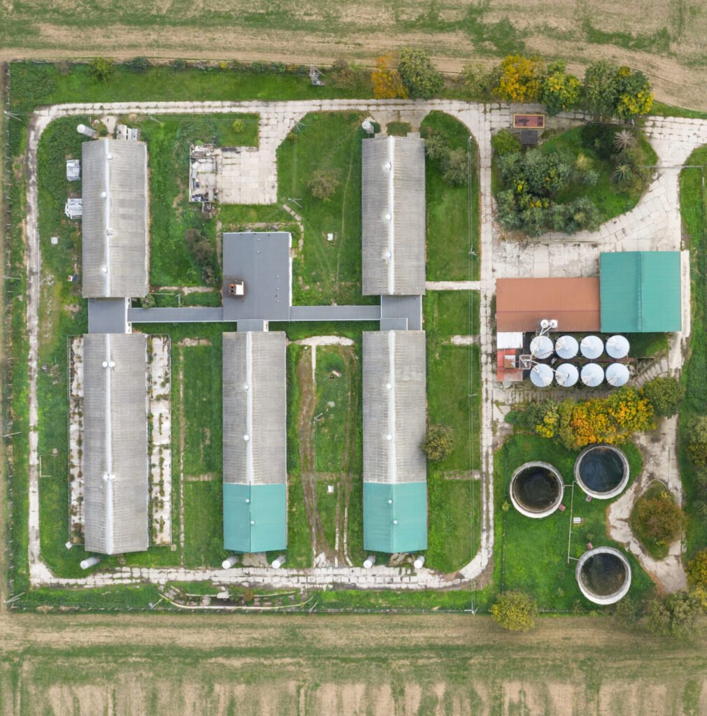Aerial view of a farm including barns and a gravel drive leading to a paved road.