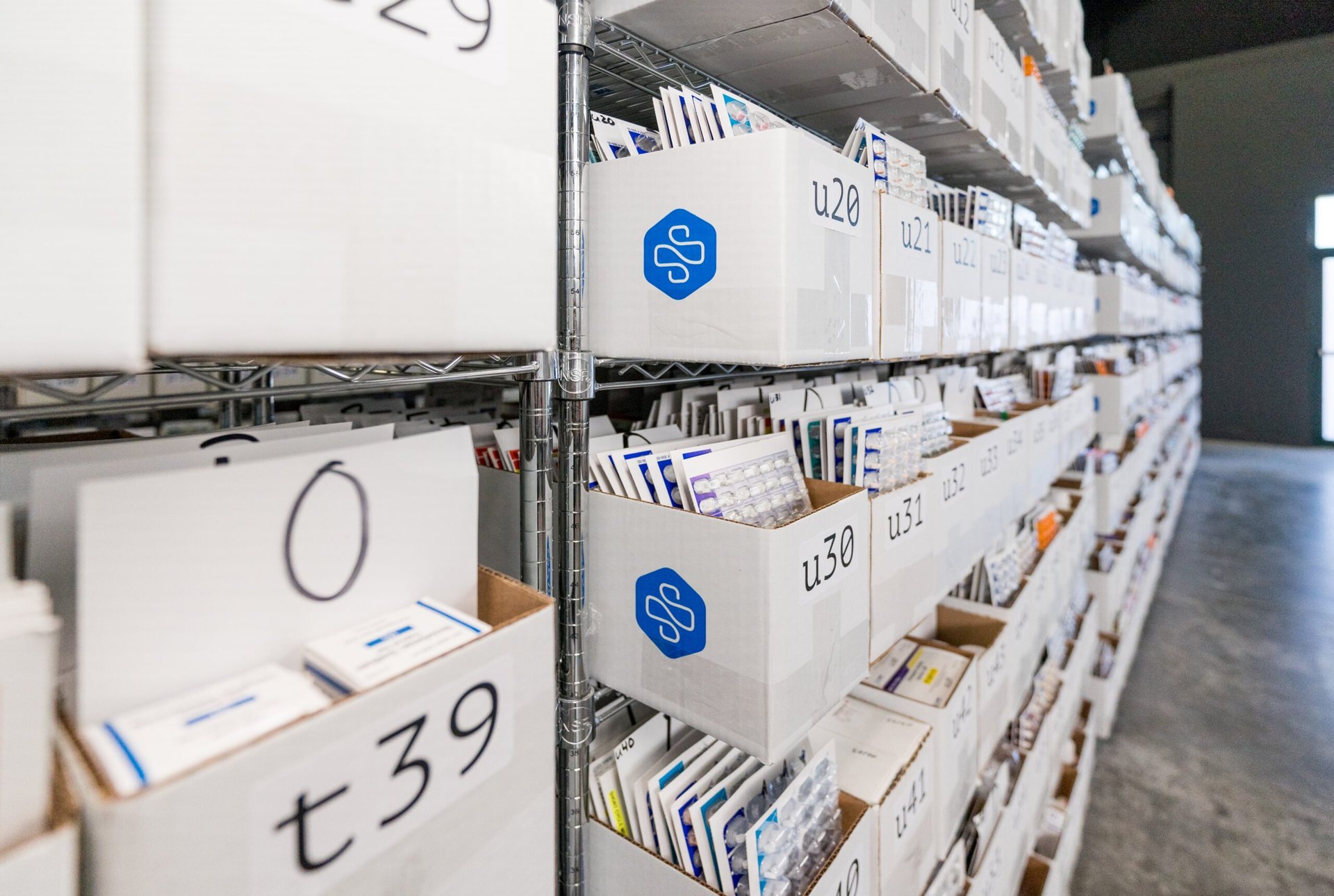 SIRUM Photo of a warehouse with stacked white sorting bins with medicines