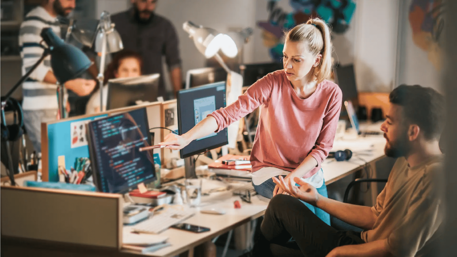 Man checking tablet in front of larger screen of figures