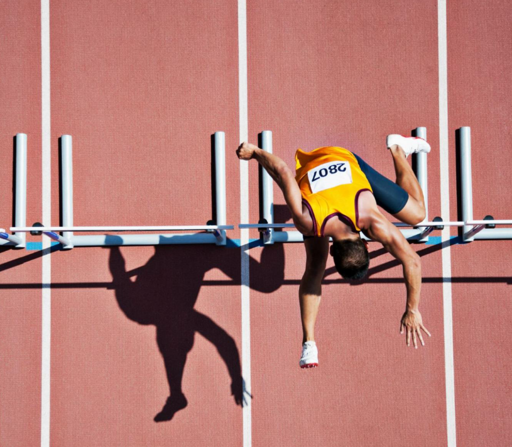 Overhead view of a running man jumping over a hurdle